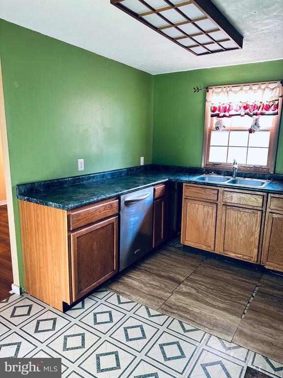 kitchen featuring dark countertops, stainless steel dishwasher, and a sink