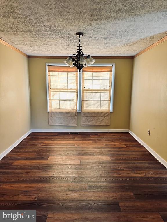 unfurnished dining area with a chandelier, a healthy amount of sunlight, and wood finished floors