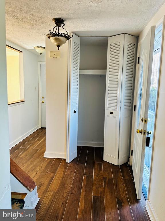 unfurnished bedroom featuring dark wood-style floors, baseboards, a textured ceiling, and a closet