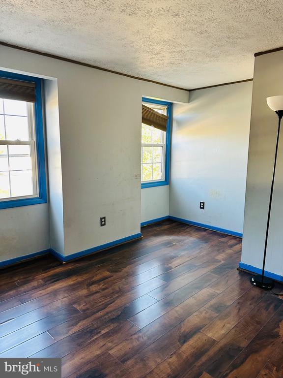 empty room with hardwood / wood-style flooring, baseboards, and a textured ceiling