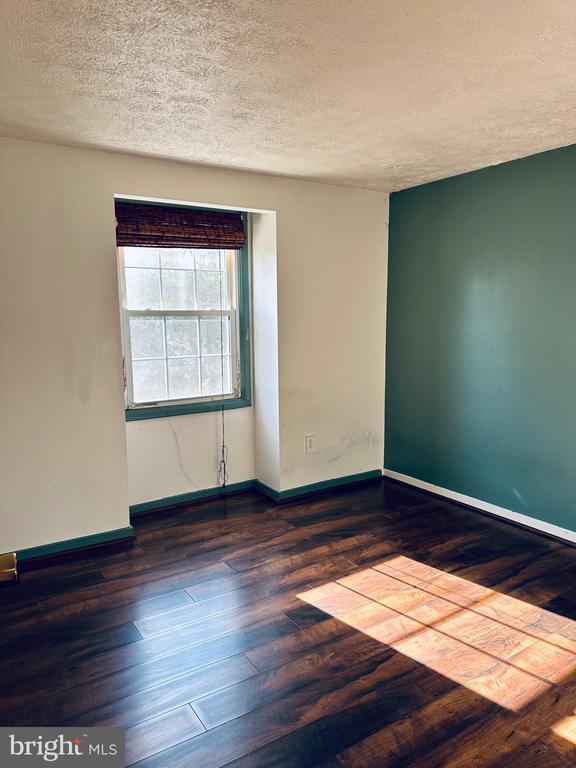 spare room featuring baseboards, a textured ceiling, and hardwood / wood-style flooring