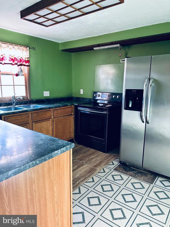 kitchen featuring dark countertops, black electric range, stainless steel fridge, and a sink