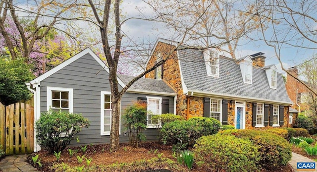 view of front of property with a chimney, stone siding, and fence