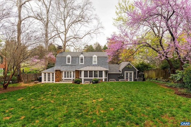 rear view of house featuring a chimney, french doors, and a fenced backyard