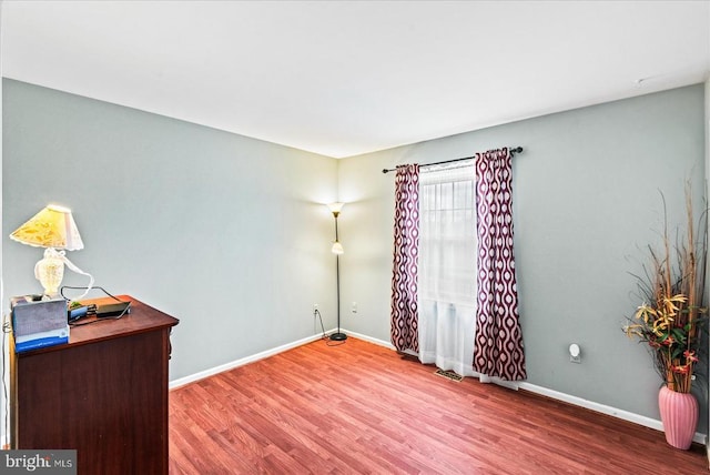 spare room featuring wood finished floors, baseboards, and an office area
