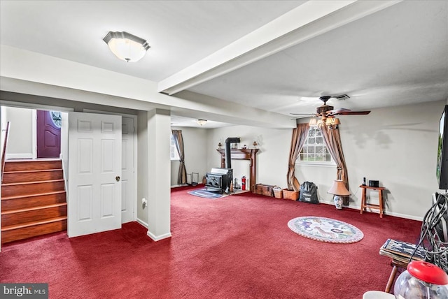 playroom with a wood stove, carpet, ceiling fan, and baseboards