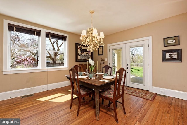 dining area featuring baseboards, a chandelier, wood finished floors, and french doors