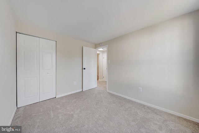 unfurnished bedroom featuring baseboards, carpet flooring, and a closet