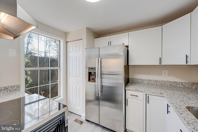 kitchen featuring white cabinetry, stainless steel fridge with ice dispenser, extractor fan, and light stone countertops