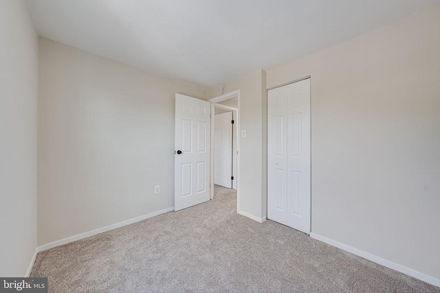 unfurnished bedroom with baseboards, carpet flooring, and a closet