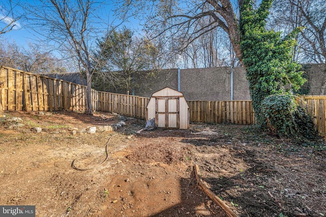 view of yard with an outdoor structure, a fenced backyard, and a shed