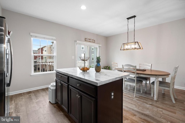  - kitchen with stainless steel refrigerator with ice dispenser, wood finished floors, a chandelier, hanging light fixtures, and baseboards