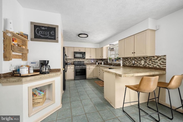 13104 Willow Point Dr, Fredericksburg, VA 22408 - kitchen featuring black appliances, cream cabinetry, a peninsula, decorative backsplash, and a textured ceiling