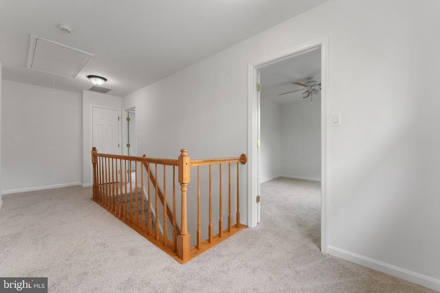 hall featuring attic access, an upstairs landing, carpet flooring, and baseboards