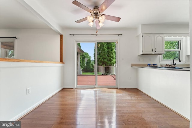 unfurnished dining area featuring healthy amount of natural light, light wood-style flooring, and a ceiling fan