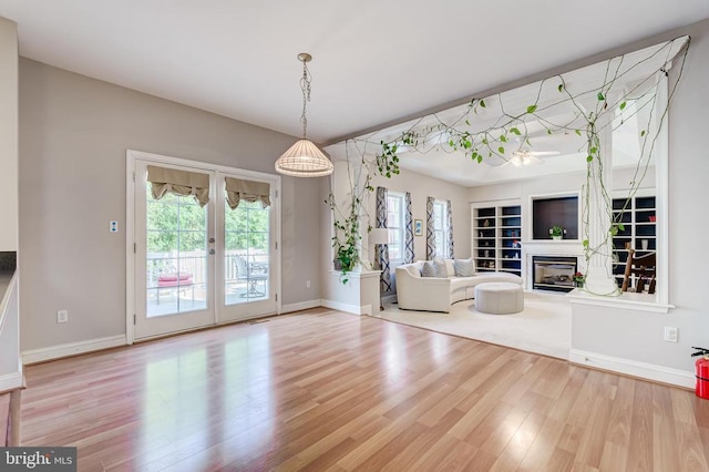 unfurnished living room featuring wood finished floors, a glass covered fireplace, and baseboards