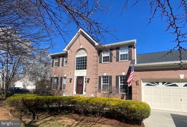 view of front of property with brick siding, an attached garage, and driveway