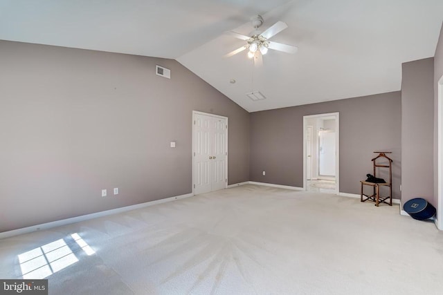 spare room featuring lofted ceiling, light colored carpet, ceiling fan, and baseboards
