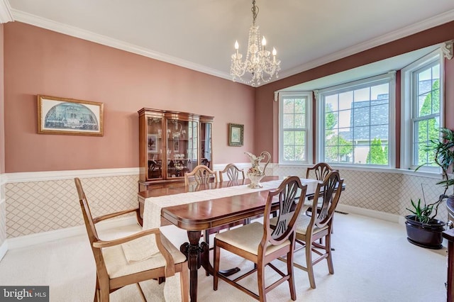 dining room with carpet, ornamental molding, a wainscoted wall, and a chandelier