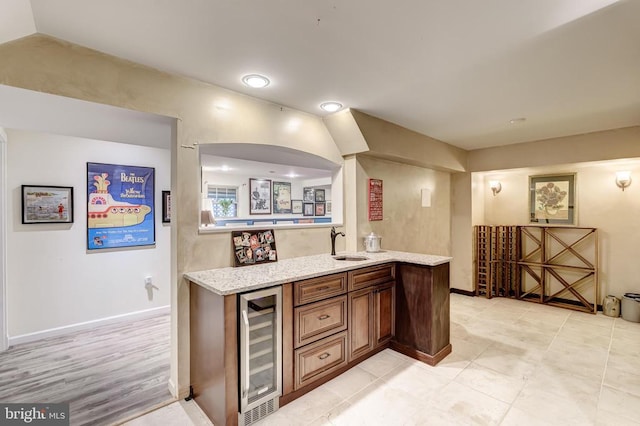 indoor wet bar featuring wine cooler, light tile patterned flooring, and baseboards