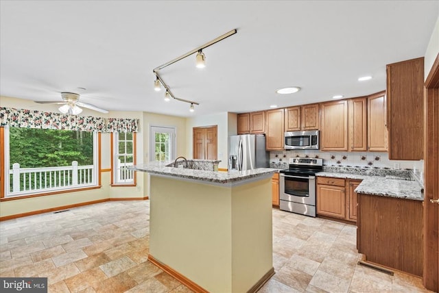 12017 Stonehenge Dr, Fredericksburg, VA 22407 - kitchen with appliances with stainless steel finishes, an island with sink, ceiling fan, light stone counters, and stone finish flooring