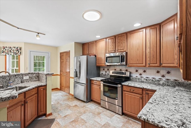 12017 Stonehenge Dr, Fredericksburg, VA 22407 - kitchen with stainless steel appliances, decorative backsplash, light stone countertops, brown cabinets, and recessed lighting