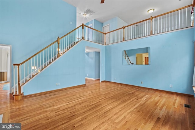 12017 Stonehenge Dr, Fredericksburg, VA 22407 - unfurnished living room featuring stairway, a high ceiling, wood finished floors, and ceiling fan