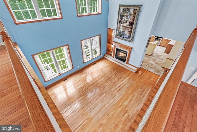 12017 Stonehenge Dr, Fredericksburg, VA 22407 - unfurnished living room featuring a glass covered fireplace, light wood-style flooring, a high ceiling, and stairs
