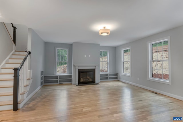 3 Lonicera Way, Charlottesville, VA 22911 - unfurnished living room with baseboards, stairway, light wood-type flooring, and a fireplace with flush hearth