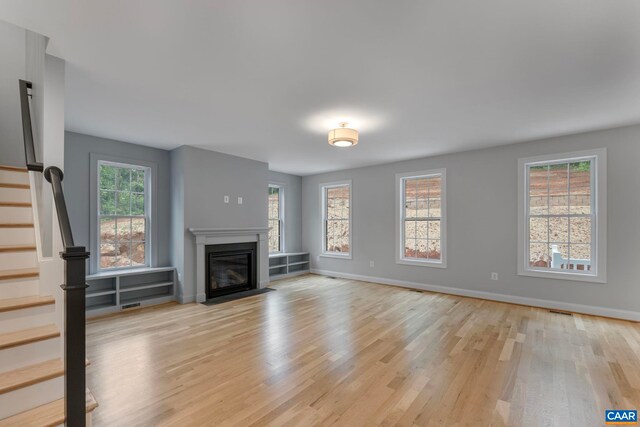 3 Lonicera Way, Charlottesville, VA 22911 - unfurnished living room featuring visible vents, stairway, light wood-style flooring, baseboards, and a fireplace with flush hearth