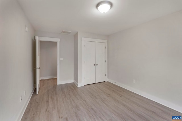 unfurnished bedroom featuring baseboards, a closet, light wood-style flooring, and visible vents