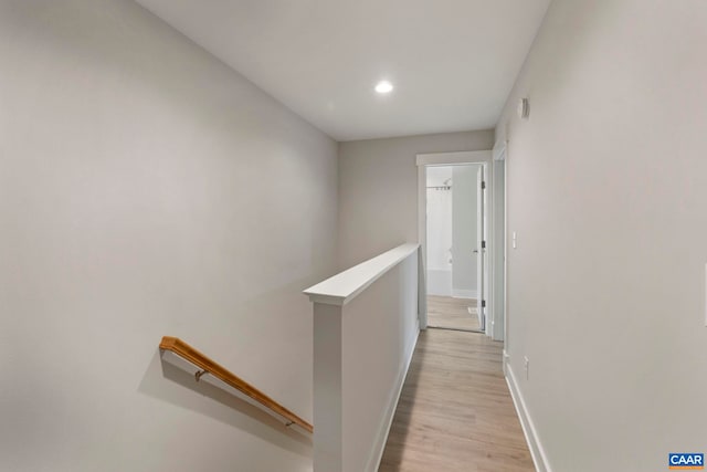 hallway featuring recessed lighting, baseboards, an upstairs landing, and light wood-style floors