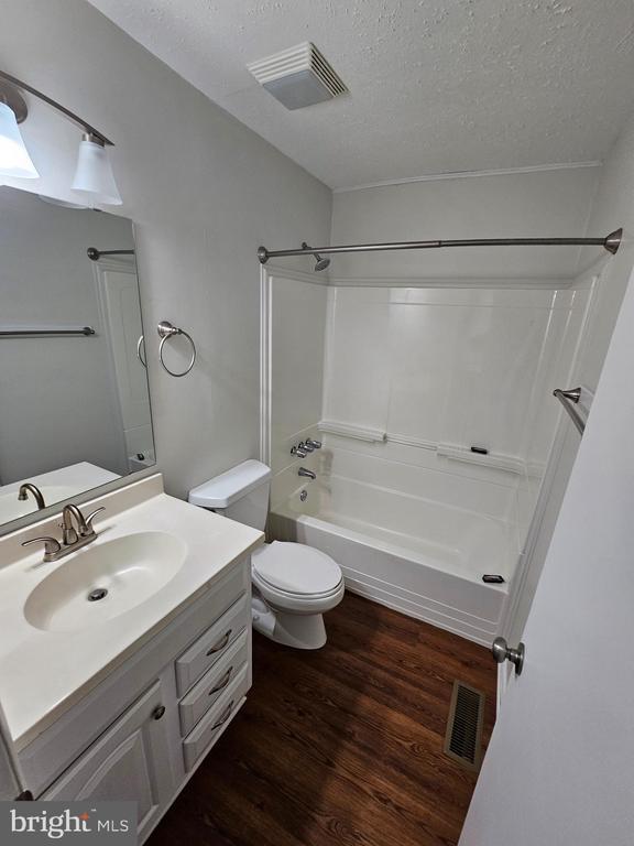 5507 Peters Ln, Fredericksburg, VA 22407 - full bath featuring a textured ceiling, wood finished floors, toilet, vanity, and  shower combination