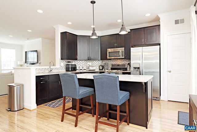 kitchen featuring tasteful backsplash, light wood-type flooring, visible vents, a center island, and appliances with stainless steel finishes