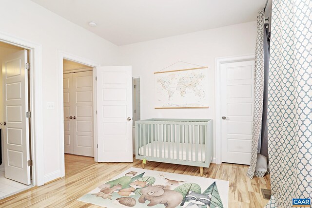 bedroom with light wood-style flooring, radiator, and a crib