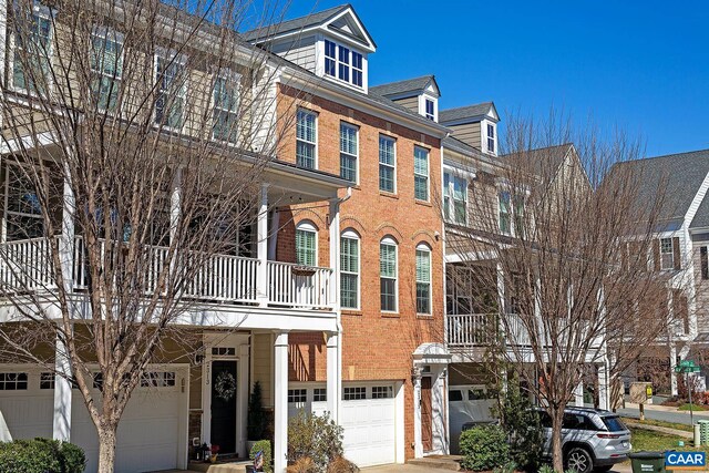 townhome / multi-family property with an attached garage, brick siding, and driveway