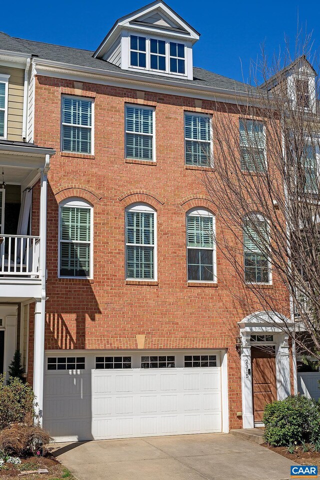 townhome / multi-family property with an attached garage, brick siding, and driveway