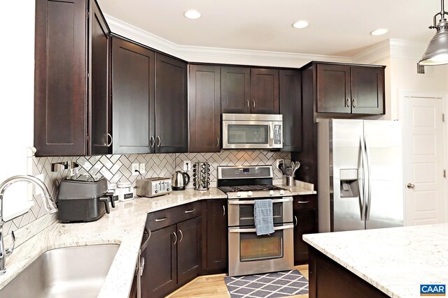 kitchen with dark brown cabinets, light stone counters, appliances with stainless steel finishes, and a sink