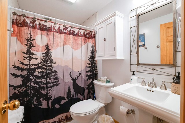 bathroom with a shower with curtain, toilet, and sink