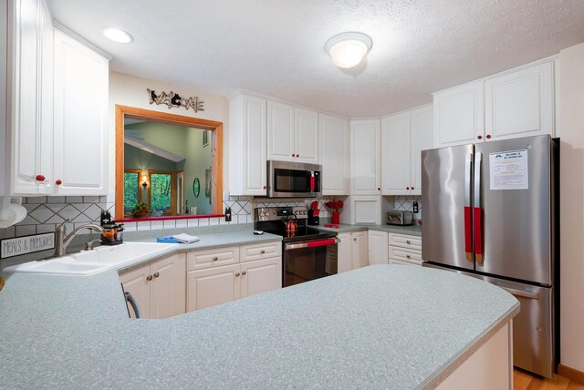 kitchen with backsplash, stainless steel appliances, and white cabinets