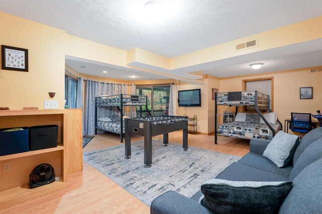 game room with light hardwood / wood-style floors and a textured ceiling