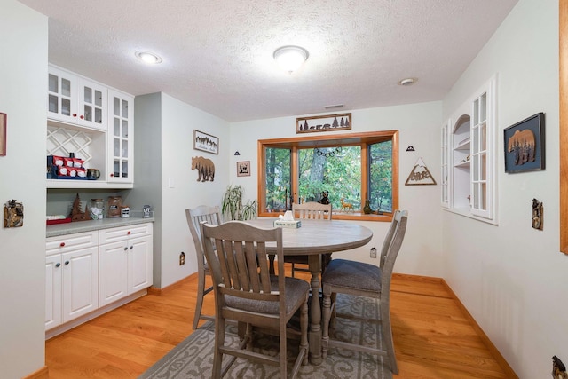 dining room featuring a textured ceiling and light wood-type flooring