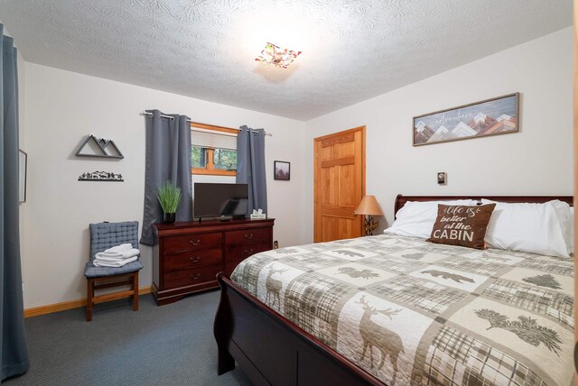 bedroom with dark colored carpet and a textured ceiling