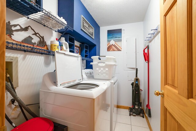 laundry room featuring light tile patterned flooring, separate washer and dryer, and a textured ceiling