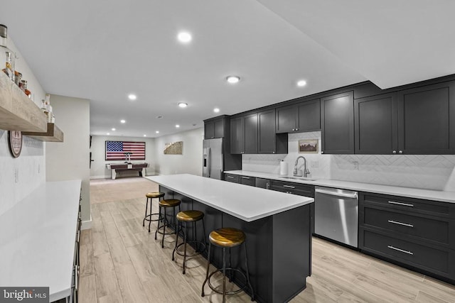 7345 Iron Bit Dr, Warrenton, VA 20186 - kitchen featuring stainless steel appliances, a sink, a breakfast bar, light countertops, and tasteful backsplash