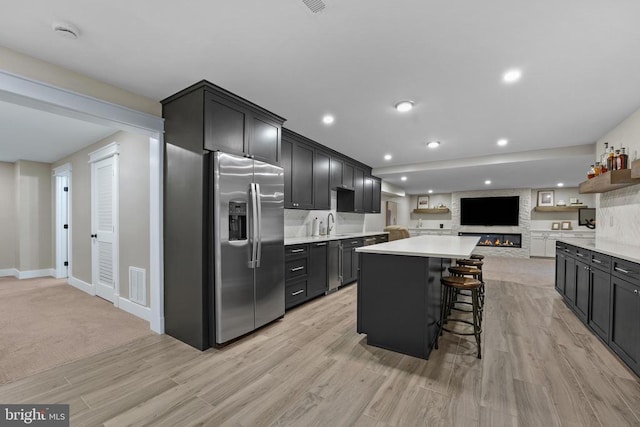 7345 Iron Bit Dr, Warrenton, VA 20186 - kitchen with stainless steel fridge, a center island, light countertops, open floor plan, and light wood-style flooring