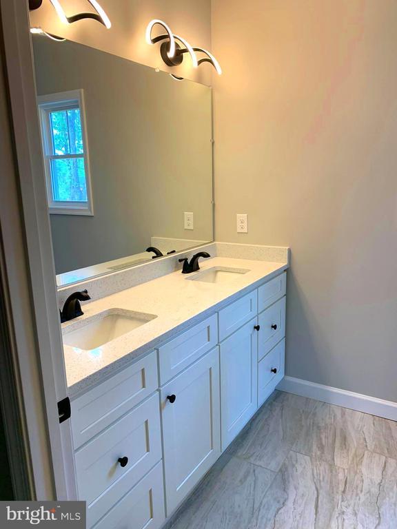 15477 Norman Rd, Culpeper, VA 22701 - bathroom featuring double vanity, marble look tiles, and baseboards