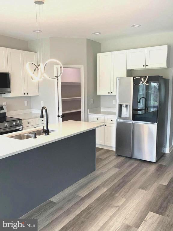 15477 Norman Rd, Culpeper, VA 22701 - kitchen with stainless steel appliances, white cabinets, wood finished floors, light countertops, and decorative light fixtures