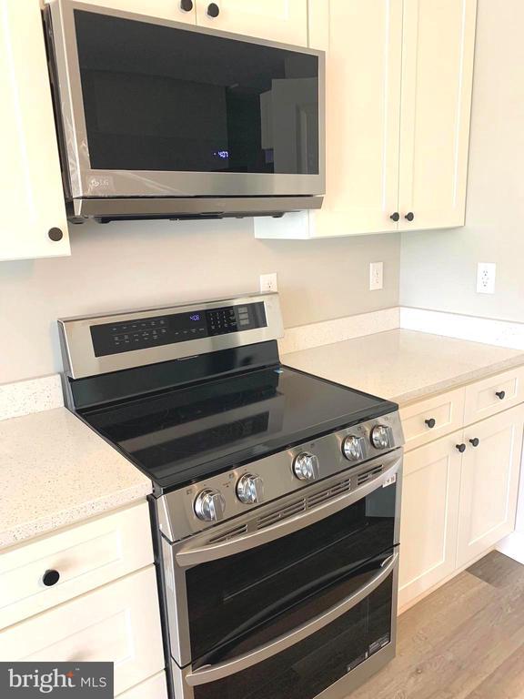 15477 Norman Rd, Culpeper, VA 22701 - kitchen featuring appliances with stainless steel finishes, wood finished floors, white cabinets, and light stone counters