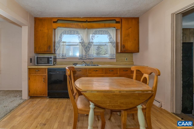 kitchen featuring brown cabinets, a sink, black dishwasher, stainless steel microwave, and light countertops
